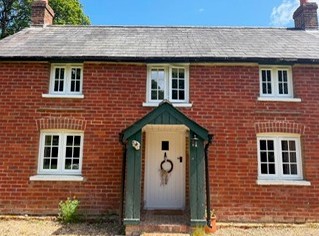Newly fitted white timber casement windows and painted porch on a red brick period cottage