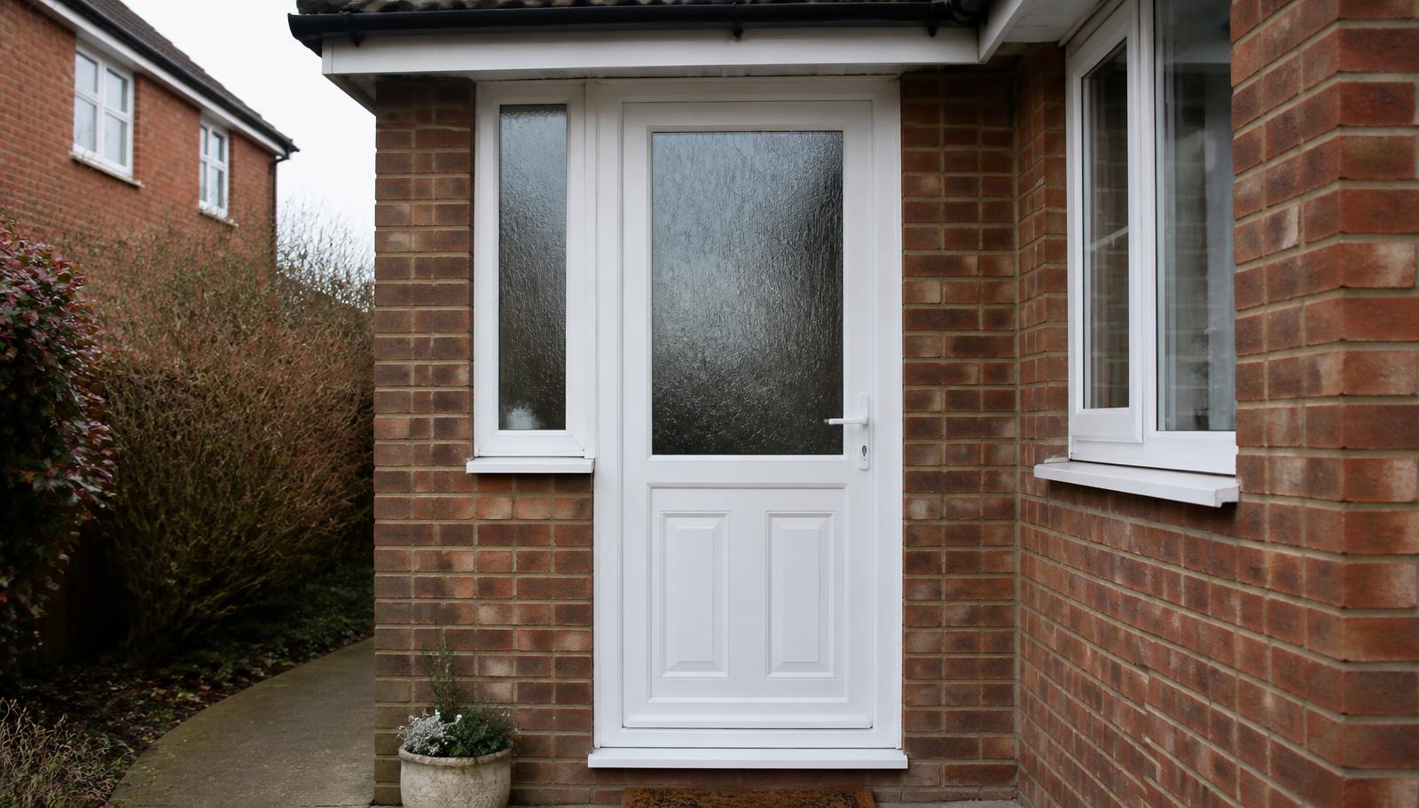 White uPVC front door with obscure glazed panel and side light in a brick porch